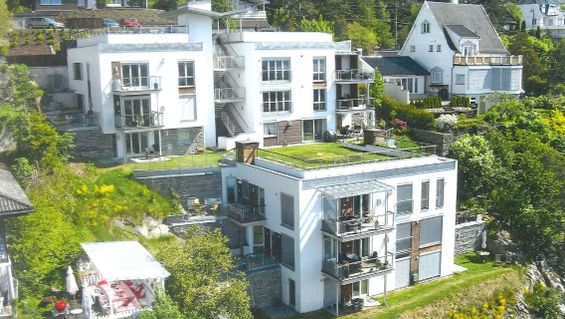 Terraserte moderne bygninger i skråning med grønne omgivelser