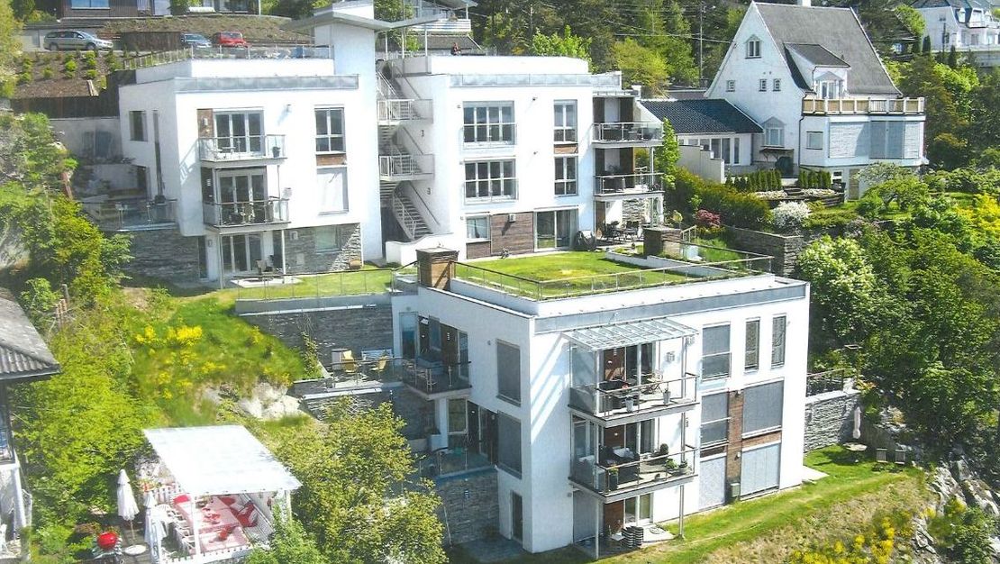 Terraserte moderne bygninger i skråning med grønne omgivelser